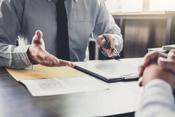 Lawyer explaining civil litigation documents to client at desk