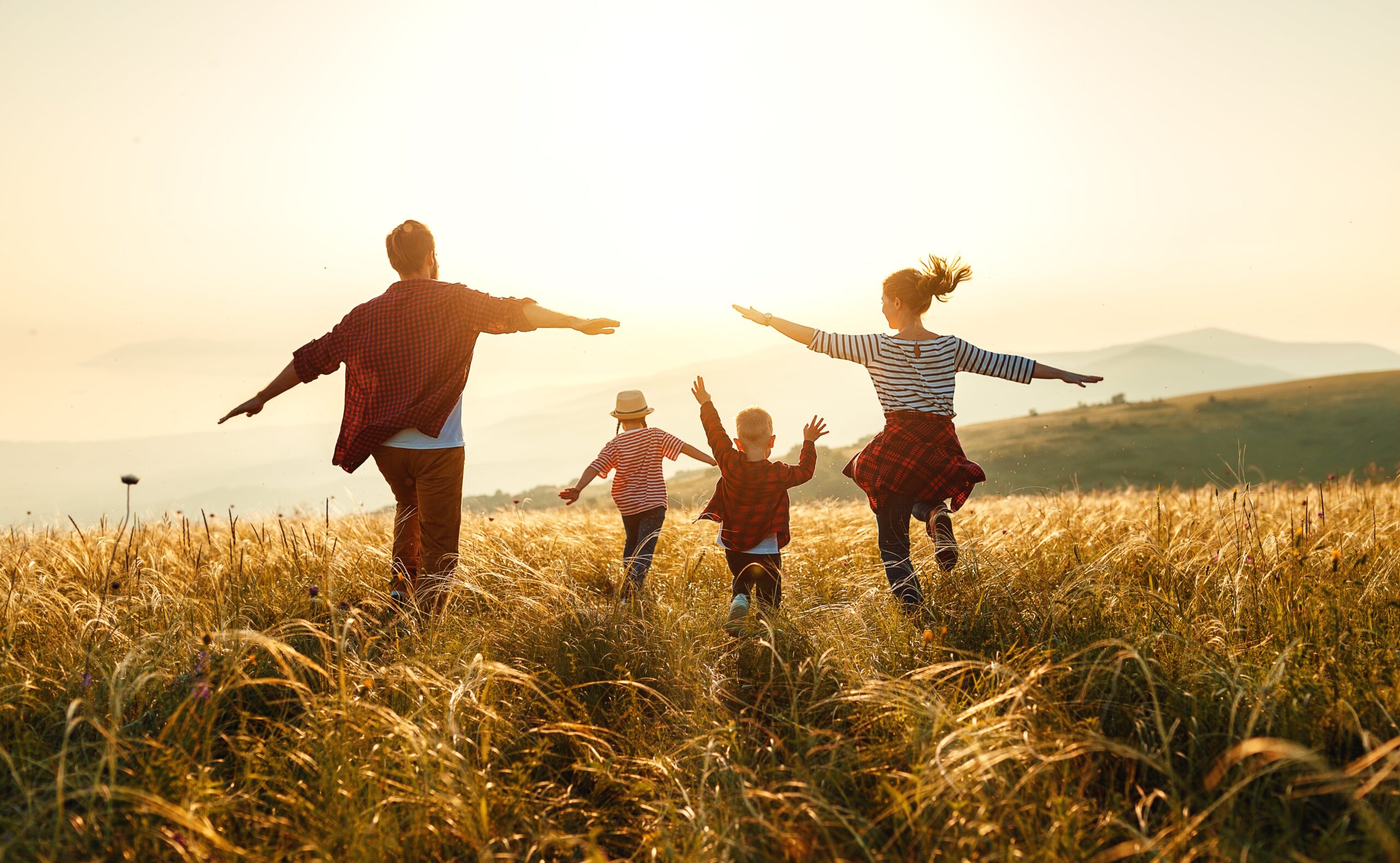 Family of four running through a field