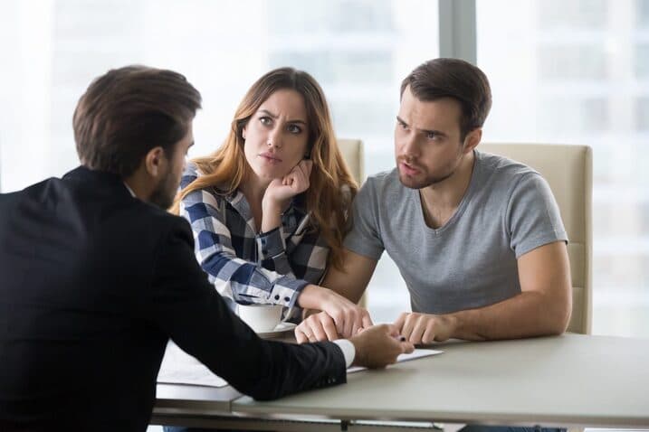 Couple discussing landlord tenant dispute with lawyer at office table