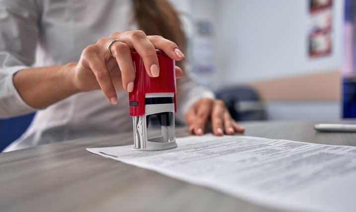 Person stamping a document with a notary seal on desk