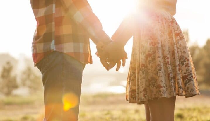Couple holding hands outdoors at sunset
