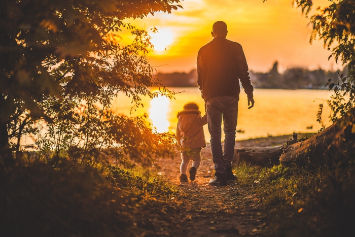 father and child walking near lake