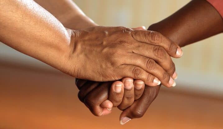 Two people holding hands in a supportive gesture