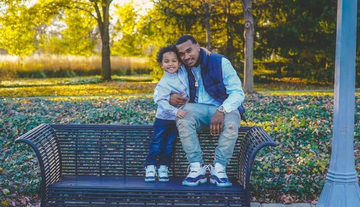 Father and young son sitting together on park bench in autumn