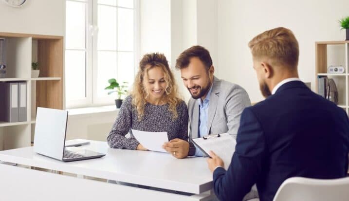 Couple reviewing estate planning documents with lawyer at office desk