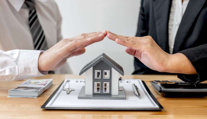The house is covered by a hand protecting to the client the buyer of the house in the real estate concept.