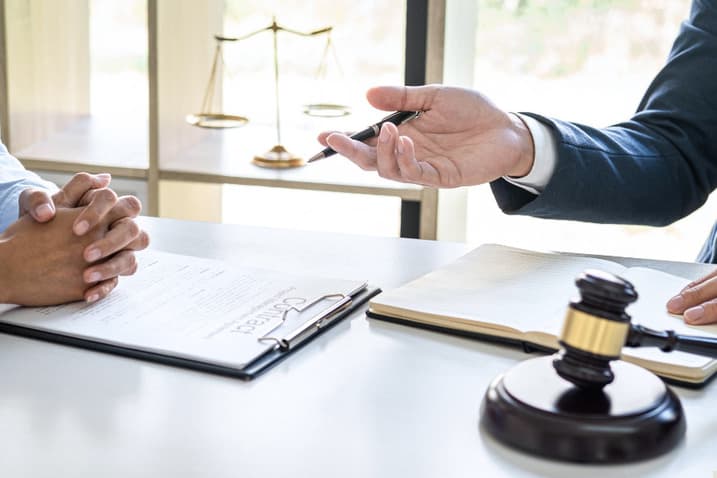 Lawyer discussing legal documents with client at desk with gavel