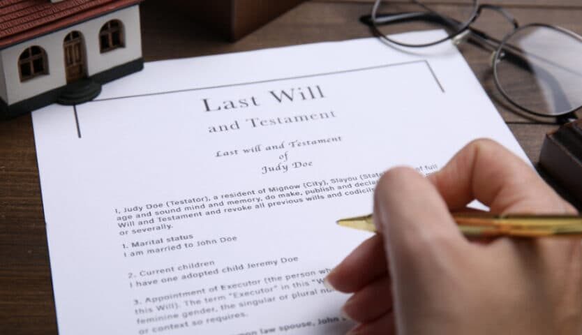 Person signing a last will and testament document on desk
