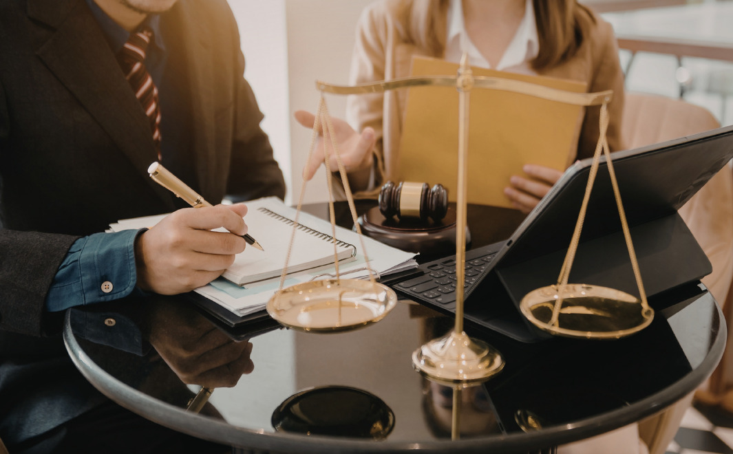 Lawyer discussing separation agreement details with client at desk with scales of justice and legal documents